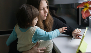 Mother using parent engagement software while holding child.
